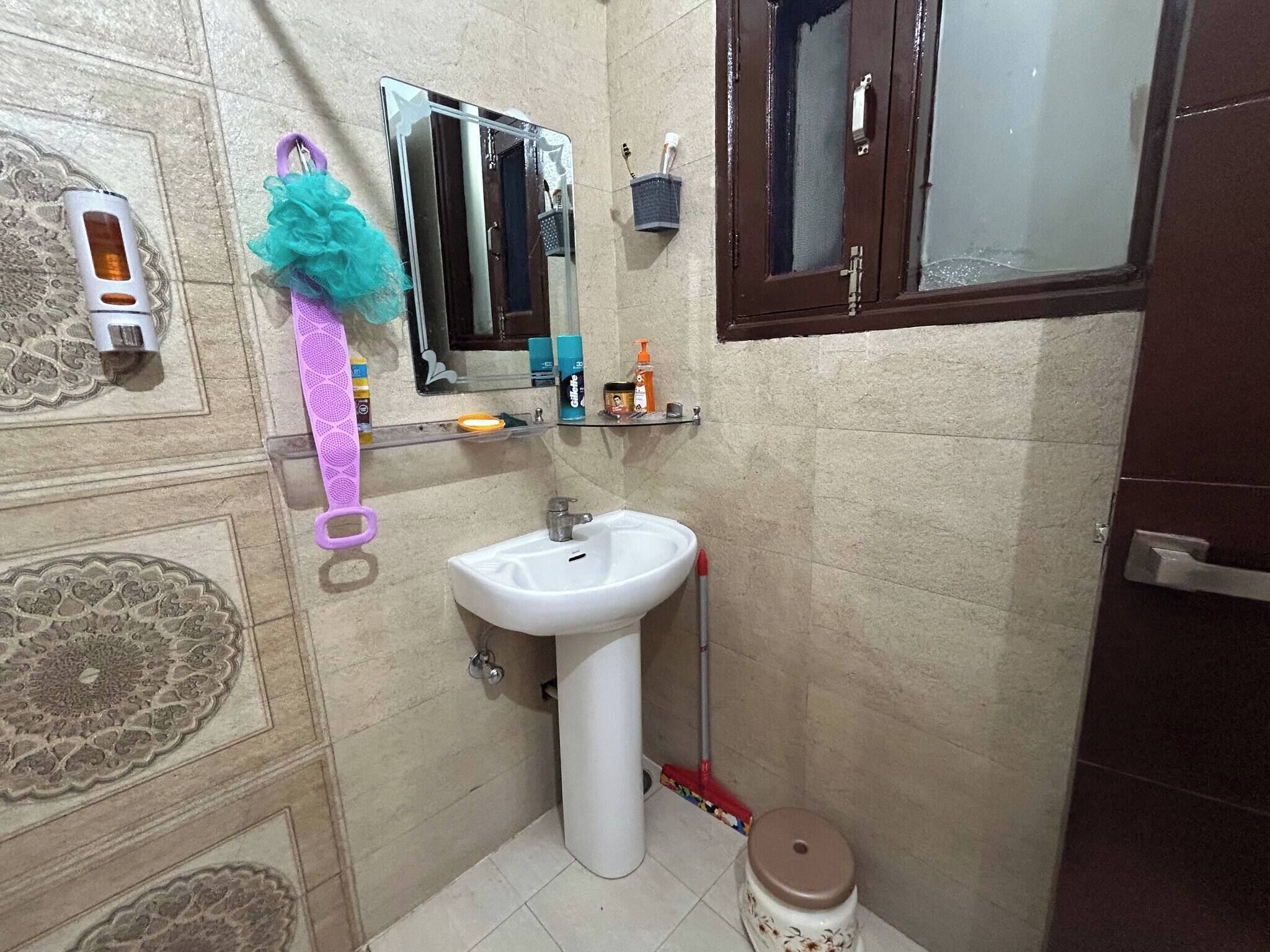 Un baño con lavamanos blanco, espejo, toallero y retrete.