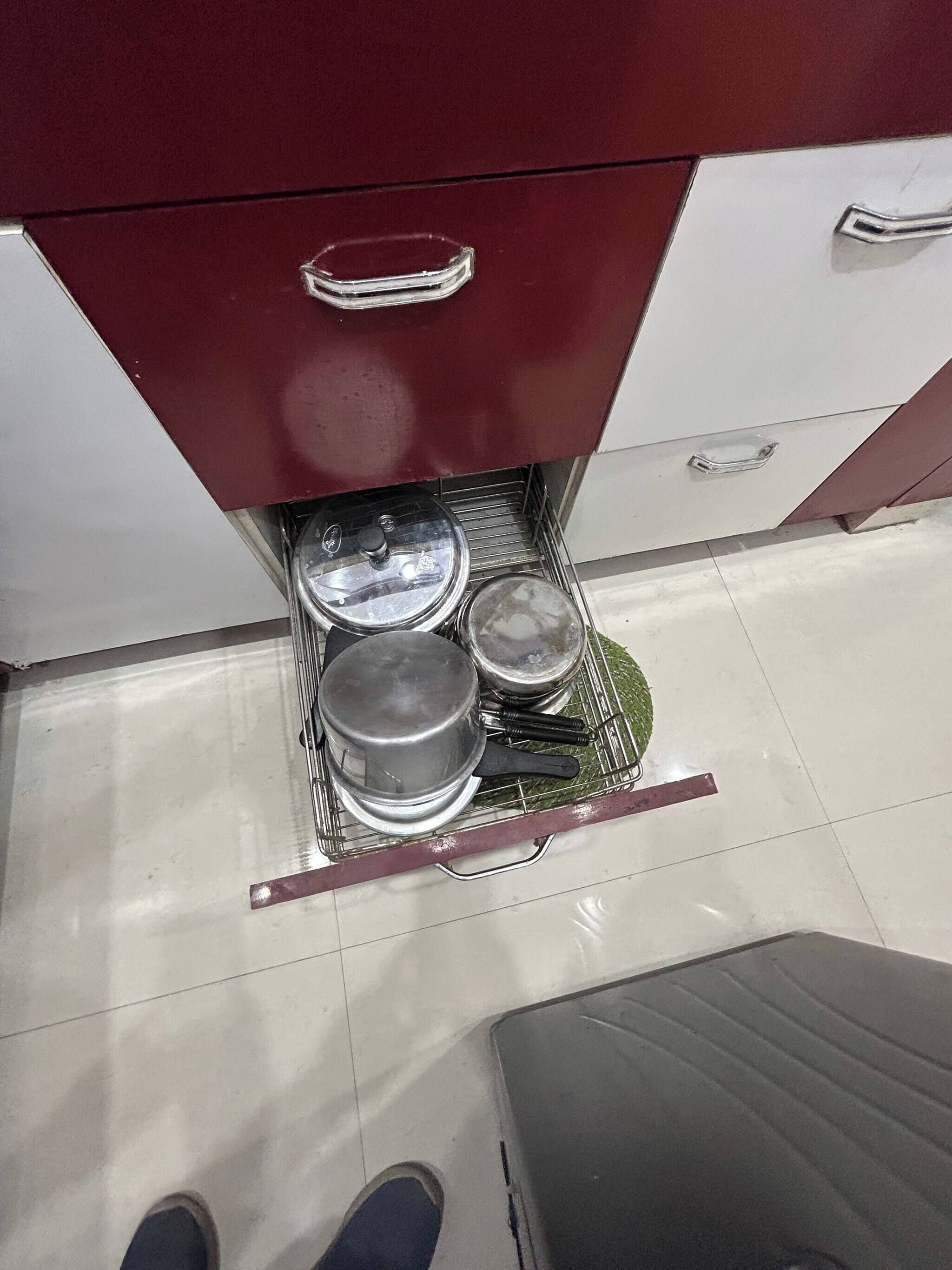 A kitchen with a drawer containing pots and pans.
