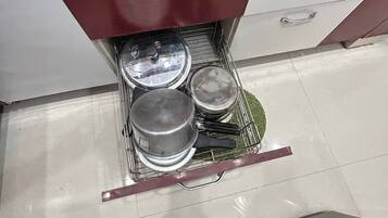 A kitchen with a drawer containing pots and pans.