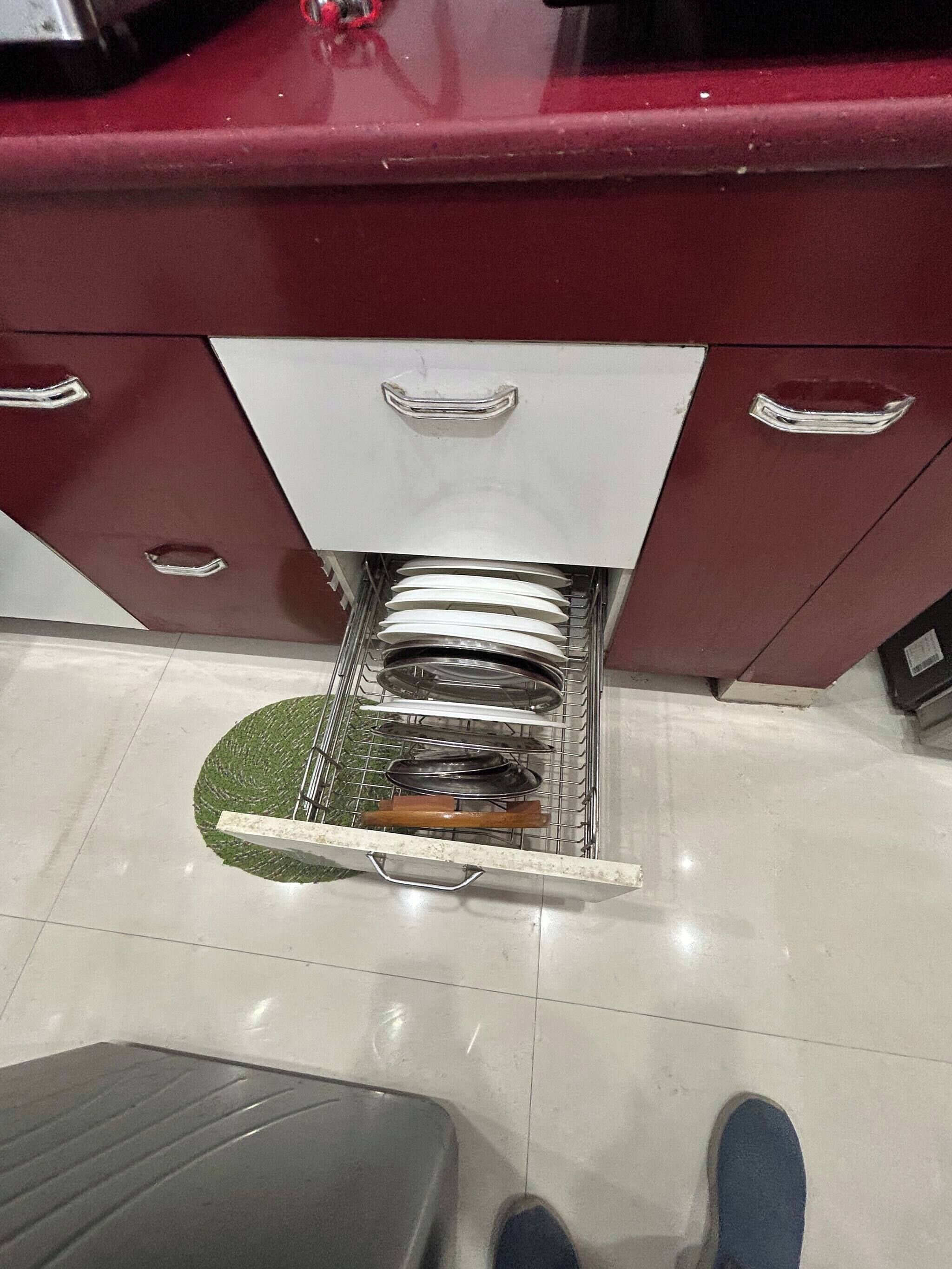 A kitchen with a stainless steel sink, a white cabinet, and a tiled floor.