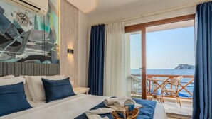 Een slaapkamer met een bed, uitzicht op zee en een balkon met stoelen.