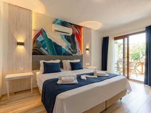 Une chambre d’hôtel moderne avec un grand lit, un tableau au mur et un balcon avec vue.