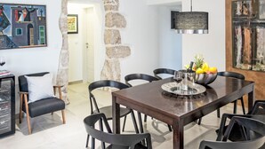 Un comedor con pared de piedra, una mesa de madera, sillas negras y un cuadro en la pared.