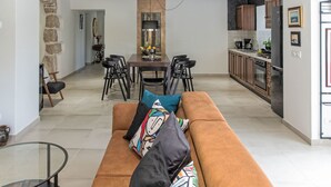 Una sala de estar moderna con un sofá marrón, una mesa de centro de cristal y un comedor con una mesa y sillas.