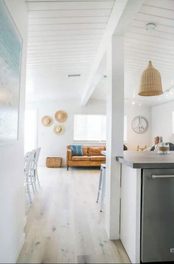 Una cocina moderna con armarios blancos, un refrigerador de acero inoxidable y una lámpara colgante.