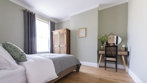 Un dormitorio con una cama, un armario de madera, un escritorio con una silla y un espejo.