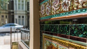 Primer plano de una pared decorativa de azulejos con diseños florales y una barandilla de metal.