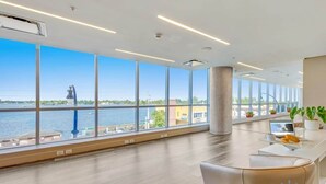 Ein modernes Hotelzimmer mit großen Fenstern und Blick auf ein Gewässer und eine Brücke.