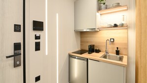 A modern kitchen with a built-in dishwasher, a stainless steel sink, and a wooden countertop. - Deos living experience 1 (Athina)