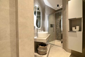 A modern bathroom with a large mirror, a sink, and a shower enclosure.