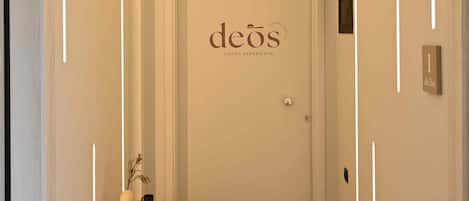 A hallway with a door labeled "deos" and a small table with a plant and a vase.