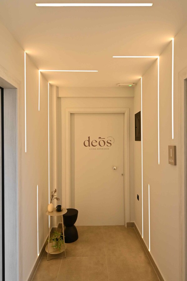 Un pasillo con una puerta que dice "deos" y una pequeña mesa con una planta y un florero.