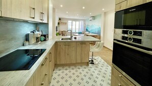 Eine moderne Küche mit Holzausstattung, einer schwarzen Induktionskochplatte und einem eingebauten Backofen.