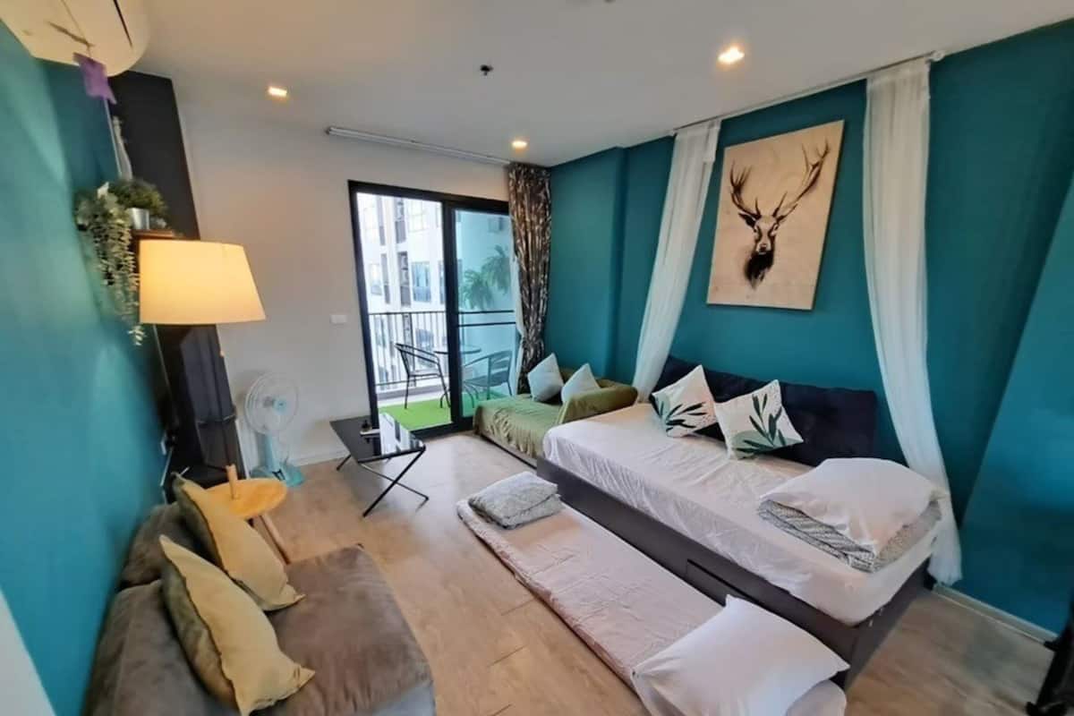 A modern hotel room with a bed, a sofa, a small table, and a balcony with a view.