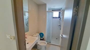 Une petite salle de bain comprenant des toilettes, un lavabo et une douche.