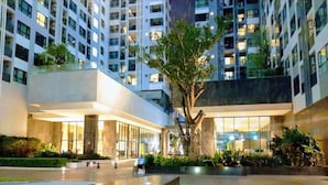Um edifício moderno com vários andares, grandes janelas e um pátio central com fonte e vegetação.