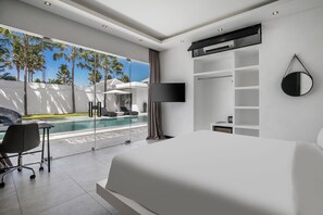 A modern hotel room with a large bed, a desk, and a view of a swimming pool and palm trees. - Mr. & Mrs. W Canggu by Alfred in Bali (Canggu)