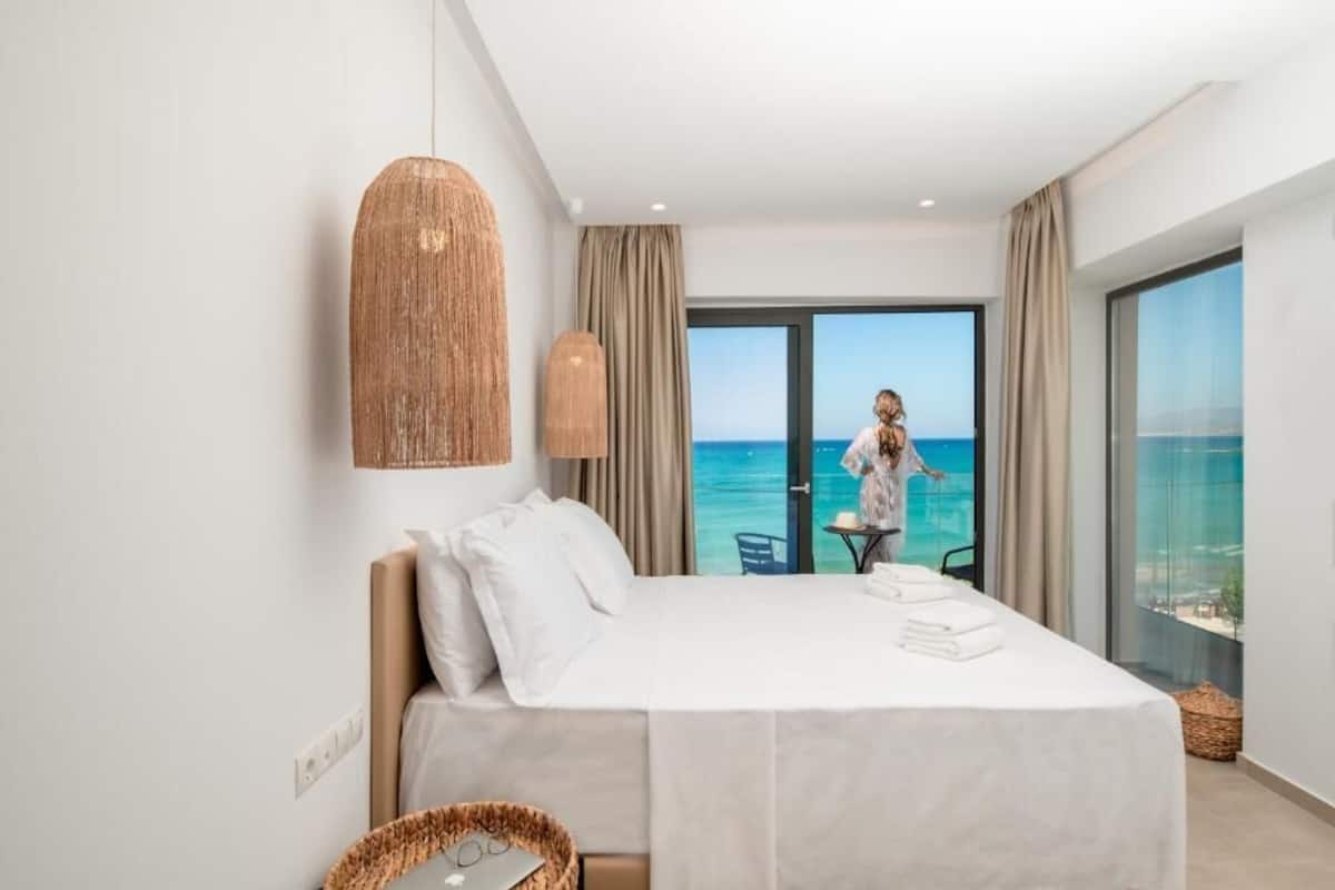 Ein Hotelzimmer mit Bett, Meerblick und einem Balkon mit Tisch und Stühlen.