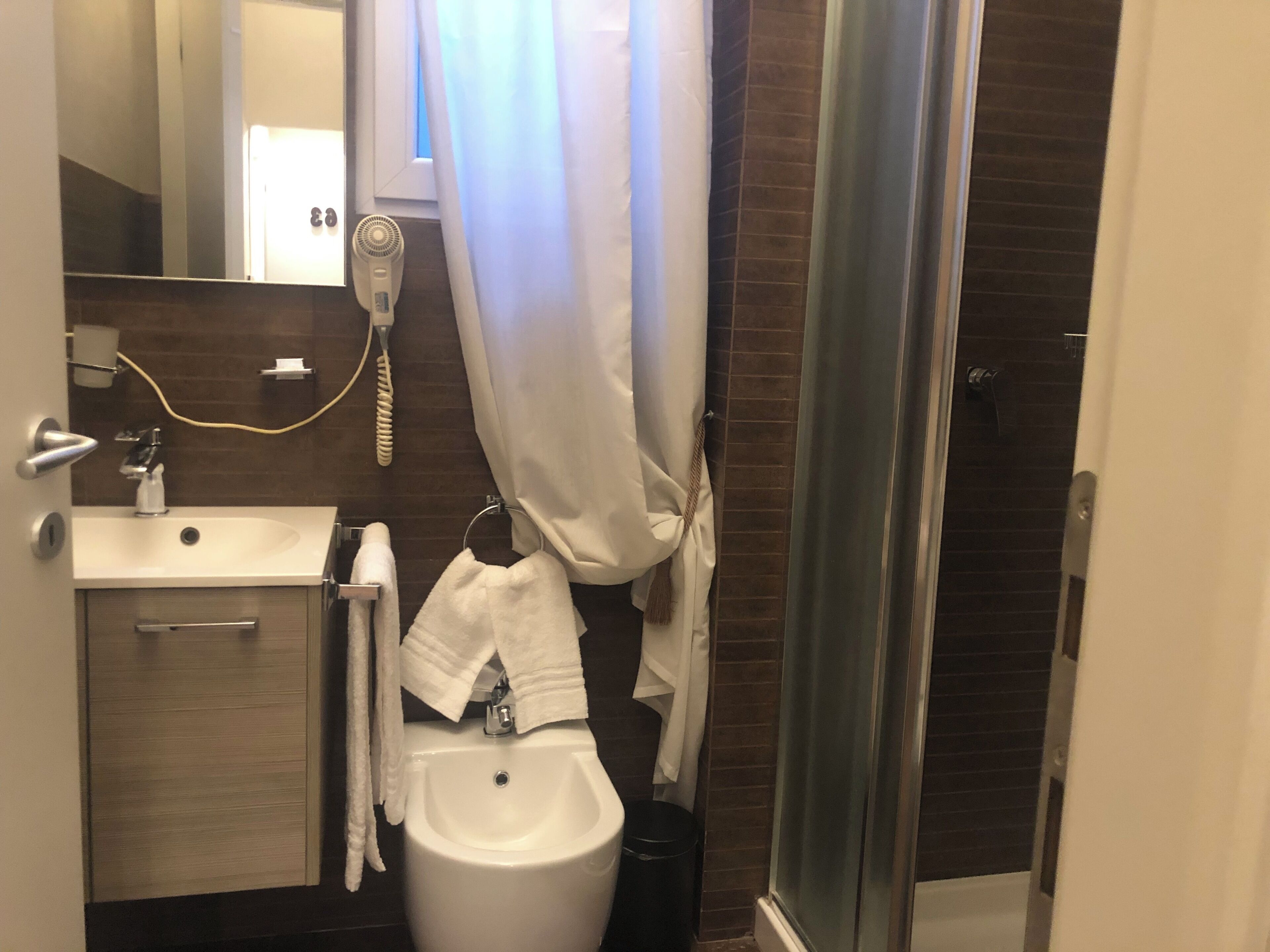 A bathroom with a sink, mirror, towel rack, and a glass shower enclosure.