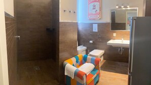 Un baño con ducha, inodoro, lavabo y una silla colorida.
