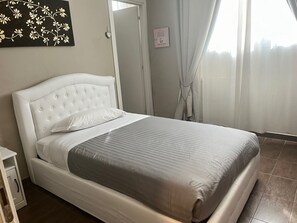 A neatly made bed with a white headboard and grey bedding, a small bedside table, and a wall decoration. - Residenza Segrate Centro Novegro (Segrate)