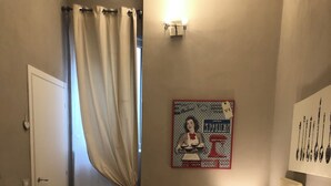 Un dormitorio con cama, almohadas, un cartel en la pared y una ventana con cortinas.