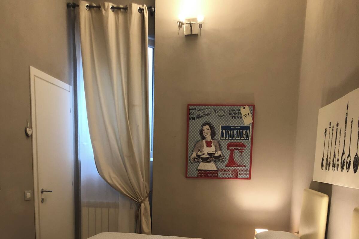 A bedroom with a bed, pillows, a poster on the wall, and a window with curtains.