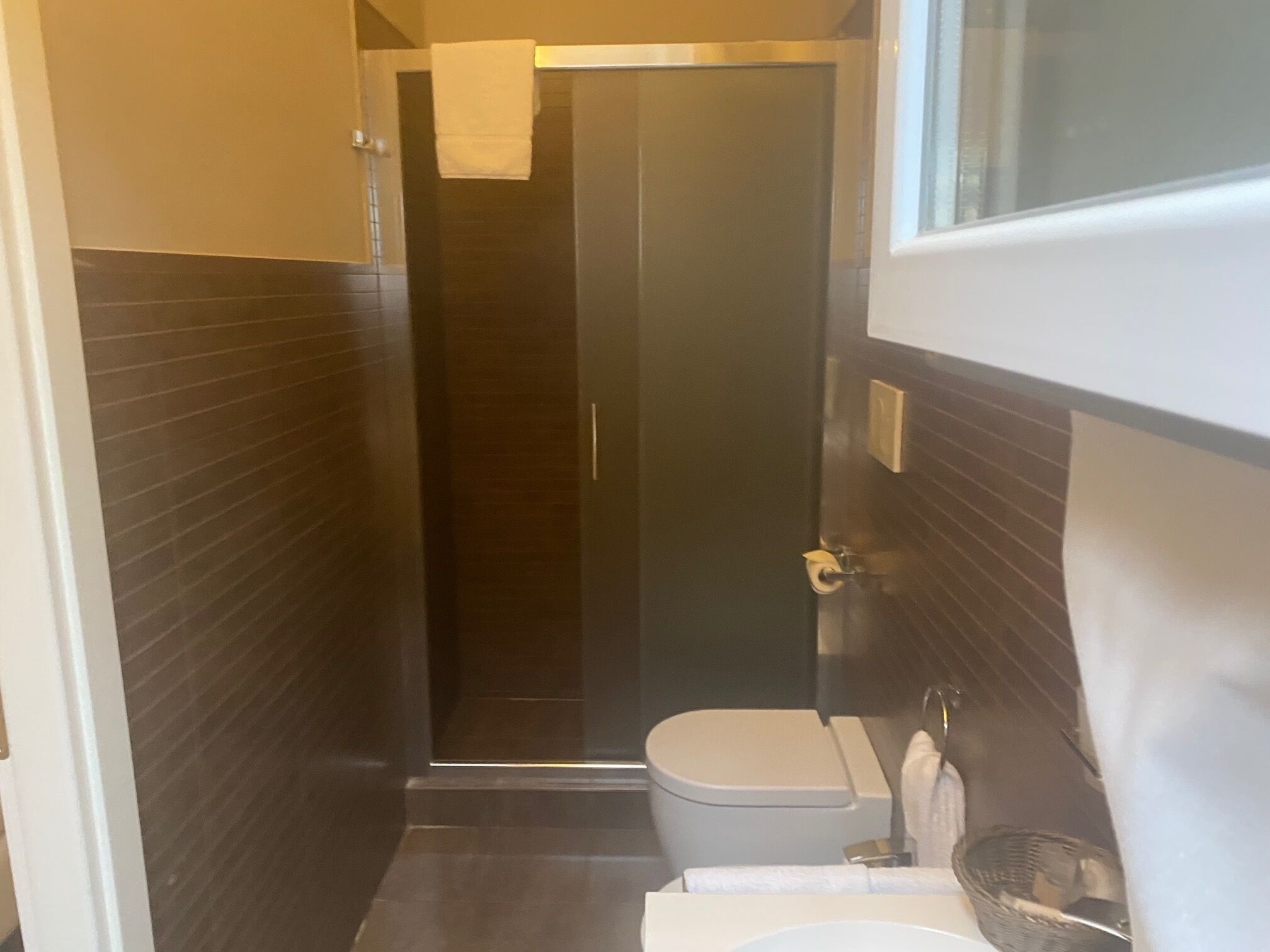 Un baño moderno con cabina de ducha de vidrio, inodoro y lavamanos.