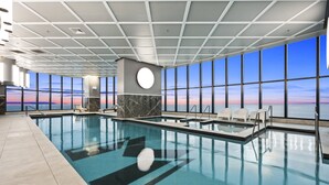 Une piscine intérieure offrant une vue dégagée sur le coucher de soleil grâce à de grandes fenêtres.