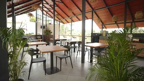 An outdoor cafe with tables and chairs, surrounded by potted plants. - Theyila Wayanad (Sulthan Bathery)