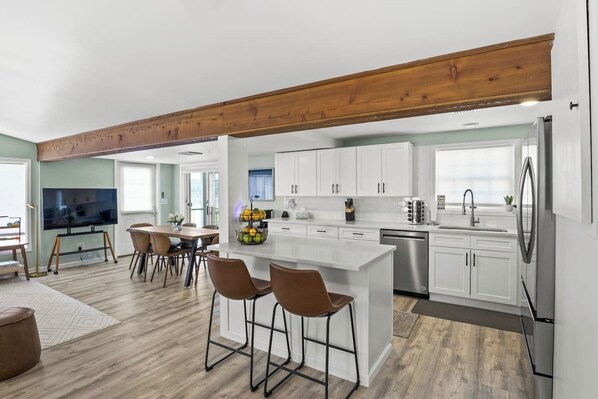 Eine moderne Küche mit weißen Schränken, einem Edelstahlkühlschrank und einem Essbereich mit Holztisch und Stühlen.