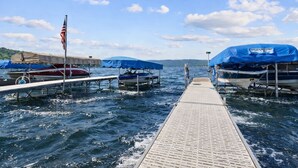 A pier with boats docked, a clear sky, and a distant shoreline. - Honeoye Lake | Hot Tub | Kayak | Fire Pit (Honeoye)