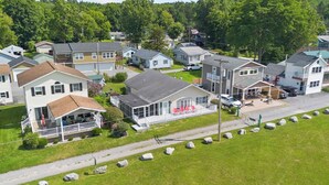 A residential area with houses, a paved road, and a grassy area with rocks. - Honeoye Lake | Hot Tub | Kayak | Fire Pit (Honeoye)