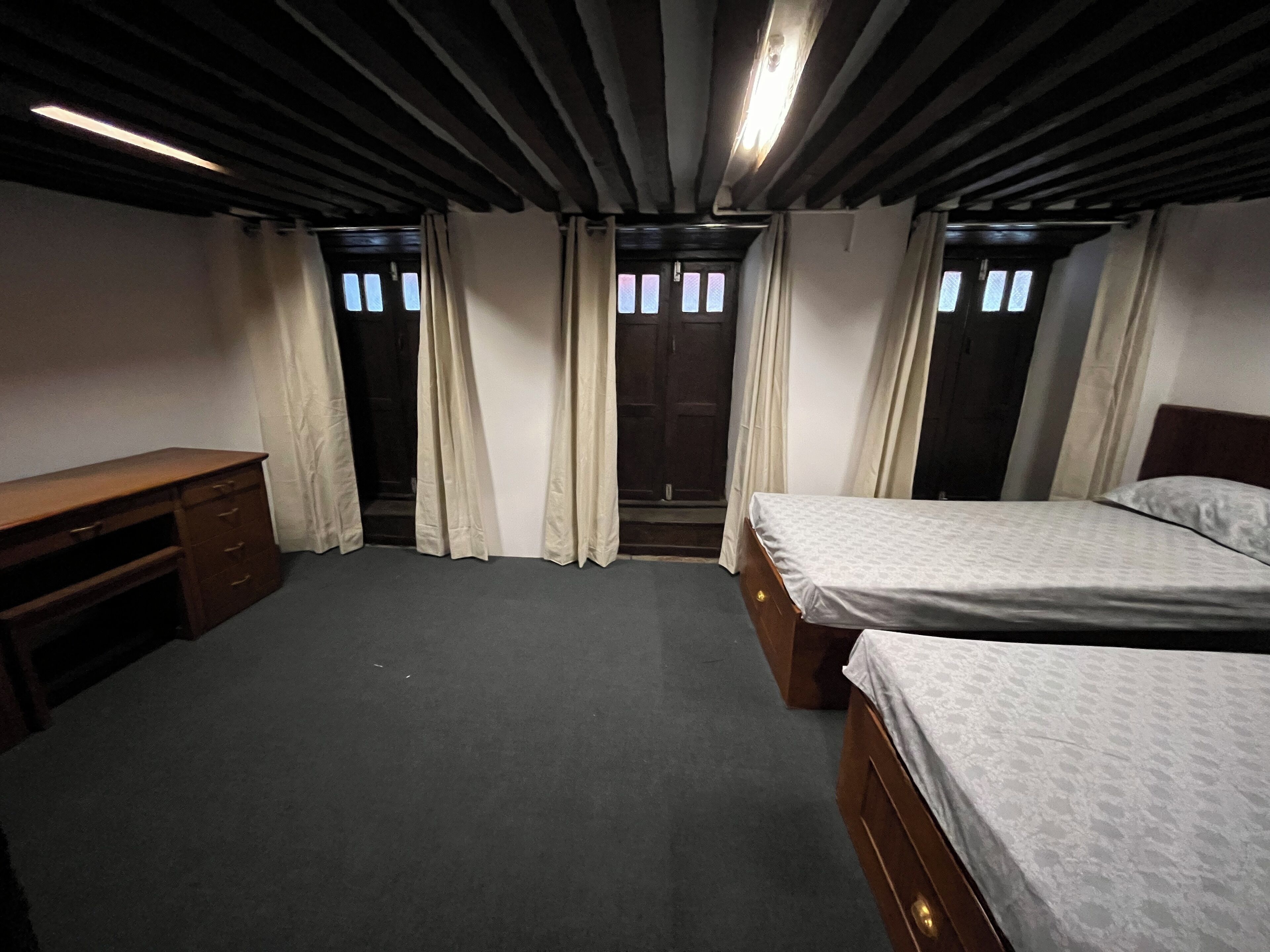 A bedroom with two beds, a wooden dresser, and a desk.