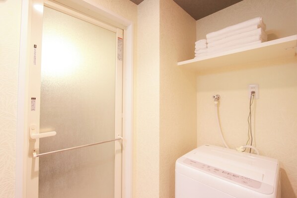 Une salle de bain avec une porte blanche, un porte-serviettes et un chauffe-eau blanc fixé au mur.