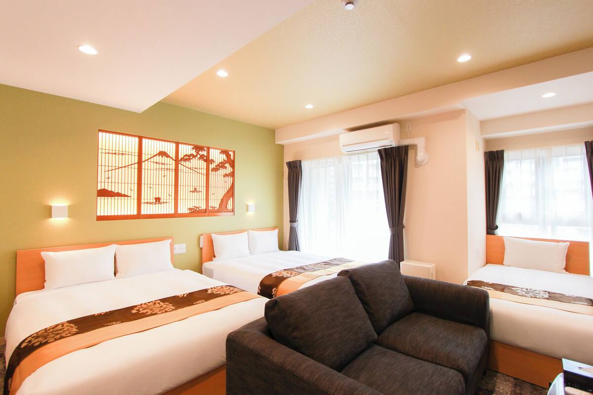 Une chambre d’hôtel avec deux lits, un canapé, un élément décoratif mural et un appareil de climatisation.