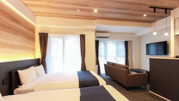 Ein Hotelzimmer mit zwei Betten, einer Couch, einem Schreibtisch und einem Fernseher.