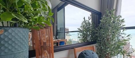 A balcony with a table, chairs, and potted plants.