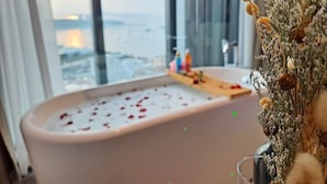 A bathtub with rose petals, a glass of water, and a decorative plant with dried flowers. - Edge Central Pattaya by Mickey (Pattaya)