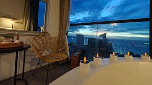A modern hotel room with a large window offering a city view at dusk. - Edge Central Pattaya by Mickey (Pattaya)