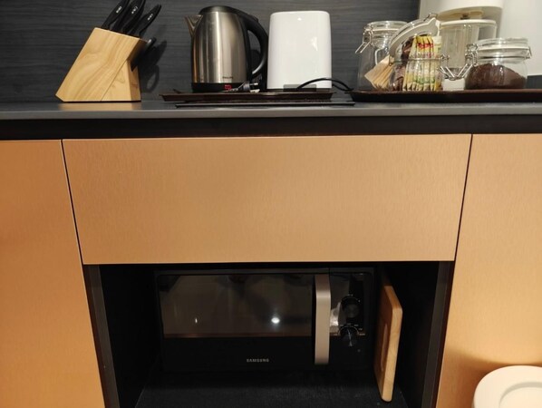 Une cuisine équipée d’un four à micro-ondes, d’une bouilloire et d’une machine à café, le tout posé sur le plan de travail.