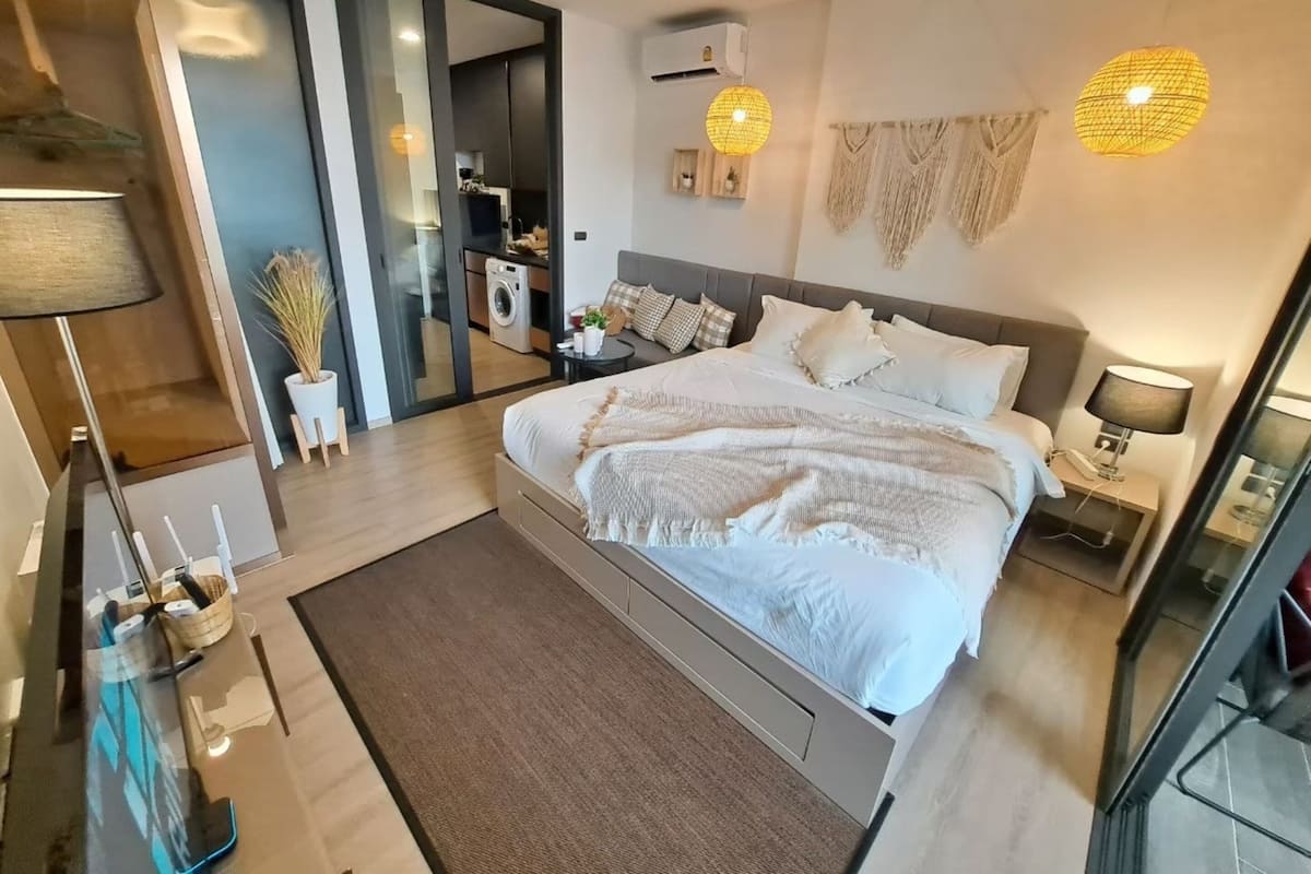 A modern bedroom with a large bed, bedside tables, a wardrobe, and a bathroom visible through an open door.