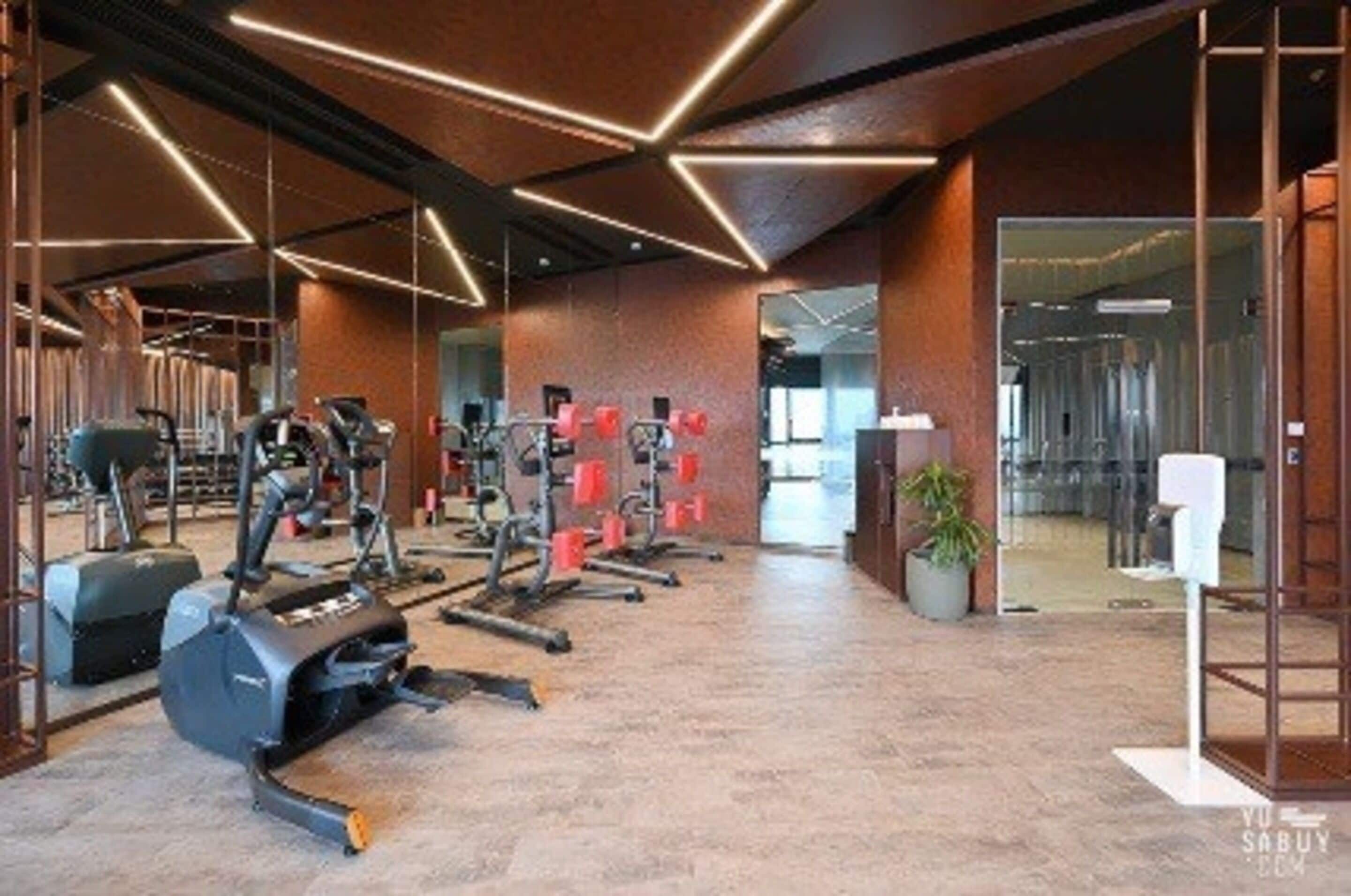 A gym with various exercise equipment, a large mirror, and a modern ceiling design.