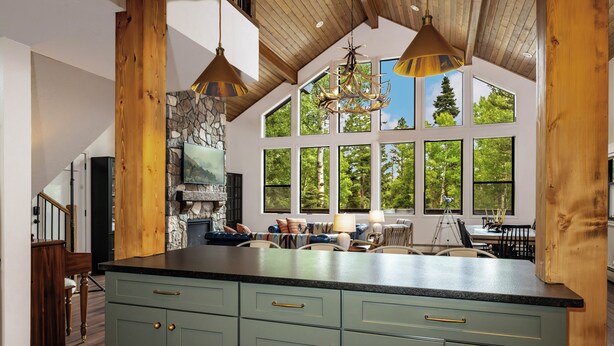 Una cocina amplia con una isla grande, chimenea de piedra y ventanas panorámicas con vistas al exterior.