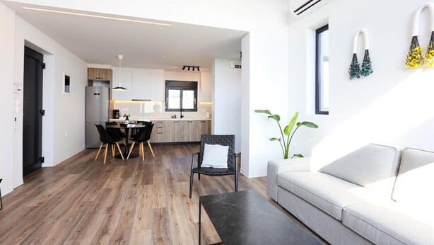Una sala de estar moderna con un sofá, una mesa de comedor con sillas y una cocina al fondo.
