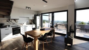 Una cocina moderna con armarios blancos, una mesa de comedor de madera y vistas al exterior.