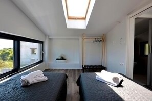 A modern hotel room with two beds, a skylight, a small plant, and a view of the outdoors. - Skiti Villas Green Holidays (Agia)