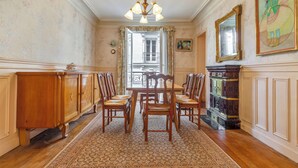 Uma sala de jantar com mesa e cadeiras de madeira, um lustre e um tapete estampado.