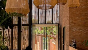 Un vestíbulo moderno con lámparas de techo de bambú, ventanas amplias y una pared de ladrillo.