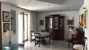 Un coin repas comprenant une table ronde, des chaises, un meuble avec des portes en verre et une lampe.